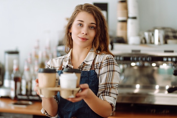 beautiful young woman serving coffee with big smile small business owner