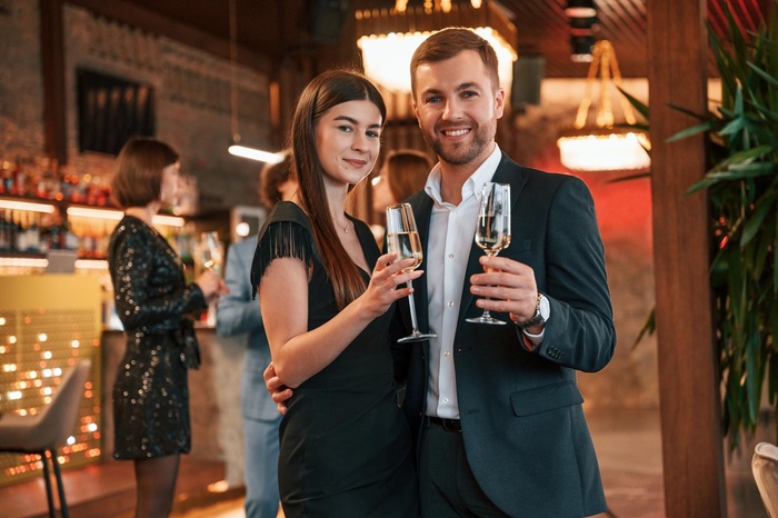 Sugar Dating Niedersachsen: stilvolles Paar stößt mit Champagner in einer Bar an – diskretes Treffen für Erwachsene